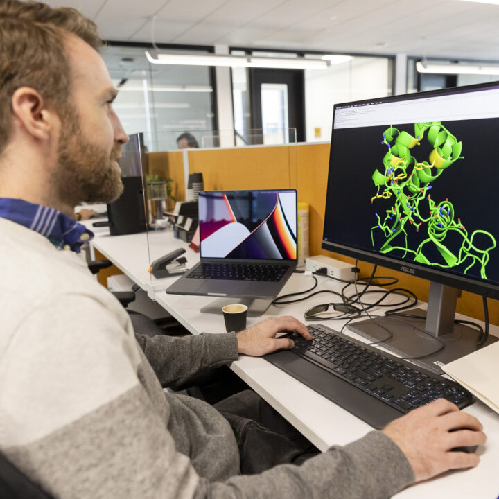 A scientist looking at a protein structure on a screen