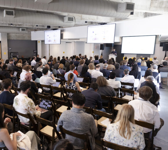 An auditorium full of people listening to a scientist talk at the podium